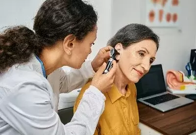 Young female doctor giving older female an ear exam