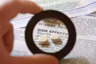 Man looking at paper through magnifying glass that says side effects