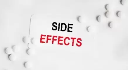 On a white vise sign SIDE EFFECTS, next to white tablets. The second word is highlighted in red.