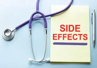 Side effect written on a yellow notepad surrounded by medical equipment