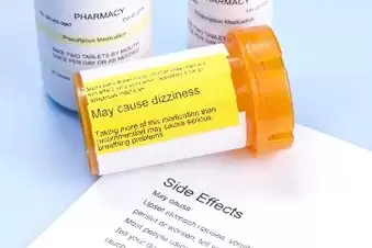 Open prescription bottle on top of insert that says side effects