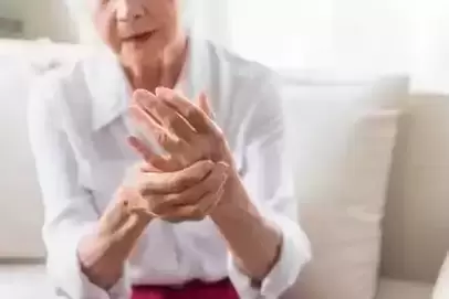 Older women holding her hand and grimising in pain
