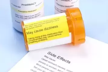 Prescription bottle with warning label and drug side effects print out.