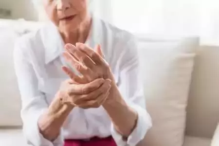 Picture of older lady holding her hand in pain from arthritis