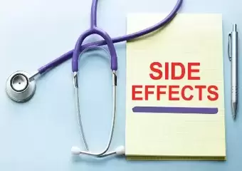 Side effect in red on yellow notebook next to a pen and stethoscope.