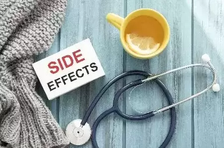Side effects text on card with tea mug and stethoscope on wooden table.