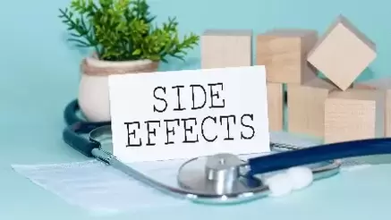 SIDE EFFECTS - words written on white medical card, with medicine mask, stethoscope, green flower and wooden blocks on background.