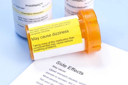 Three pill bottles with one spilt over on white paper that says side effects.